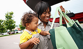 Shopping Discounts - Mother and Child Putting Groceries in the Car