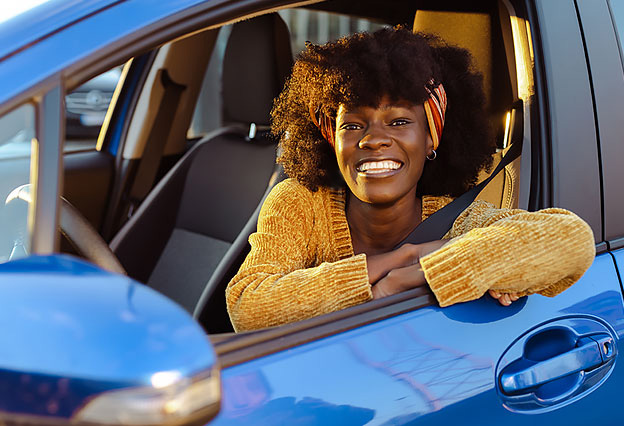 Smiling African-American Woman Sitting in the Driver's Seat of a Blue Car
