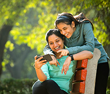 Mother and Daughter Laughing While Using Mobile Phone